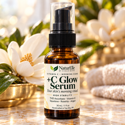 A 30 mL amber glass bottle of NaturElle by A. Rose-Coute +C Glow Serum with a black pump and clear cap, set on a marble surface with white flowers and a gold pot in the background.