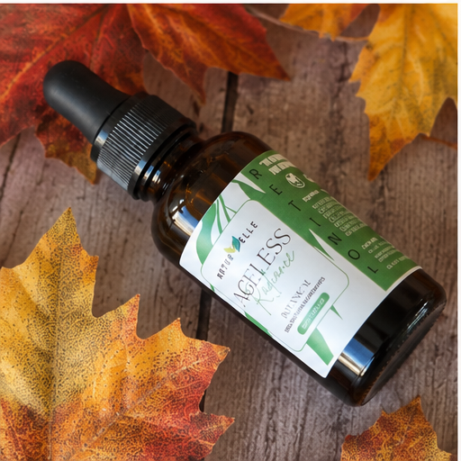Frasco del producto para el cuidado de la piel 'Ageless' recostado en una superficie de madera con hojas de otoño — NaturElle Puerto Rico