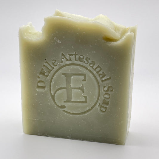 A bar of soap with 'Artisanal Soap' imprinted on it, predominantly in a light green color with a texture that appears smooth and possibly scented, set against a white background.