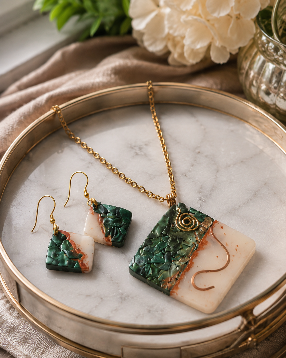 Conjunto de joyas compuesto por un collar de cadena de oro y pendientes colgantes a juego con piezas de piedra texturizada verde y blanca, presentados en una bandeja redonda de mármol con borde dorado - D'Elle Gifts
