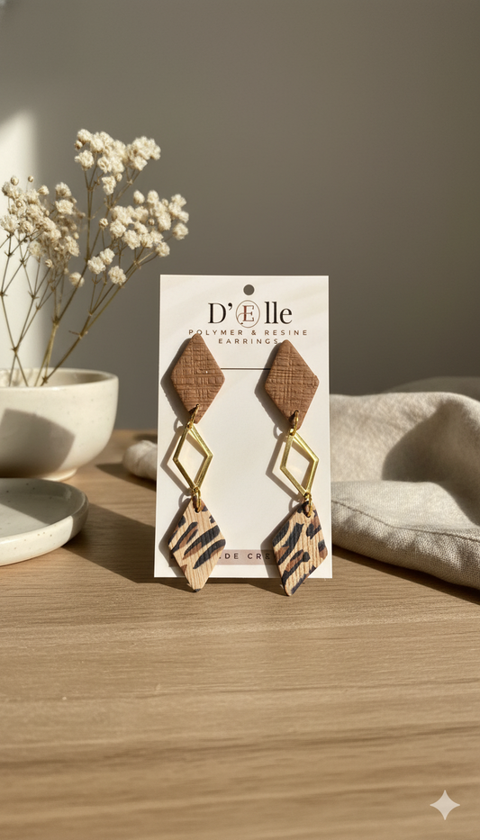 Pendientes D'Elle con estampado animal en una tarjeta de presentación con fondo neutro.