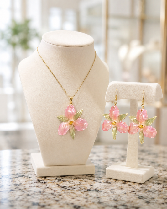 Conjunto de joyas compuesto por un collar de cadena de oro y pendientes colgantes a juego, ambos adornados con colgantes de flores rosas y hojas verdes, presentados en soportes de joyería color crema - D'Elle Gifts